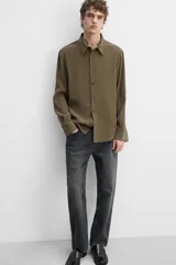 Camisa negra relaxed fit confeccionada en tejido fluido con mezcla de viscosa. Tiene cuello solapa, manga larga con puño abotonado y cierre frontal con botones.