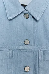 Chaqueta cropped de denim celeste claro, con cuello solapa, manga larga con puños y bolsillos de plastrón en el pecho. Cierre frontal con botones metálicos.