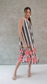 Vestido midi de corte recto con lentejuelas a rayas verticales en blanco y negro, con estampado de rosas rojas en el ruedo y ribete celeste en cuello y sisas.