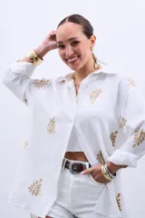 Camisa blanca de manga larga con bordado de hojas doradas.