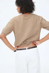 Buzo color beige de punto fino suave con cuello redondo y mangas cortas.