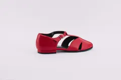 Zapatos bajos rojos de cuero, con puntera redondeada y tira central con hebilla. Presentan aberturas laterales.