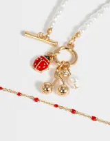 Set de dos collares dorados: uno de cadena con mostacillas rojas y otro de perlas con cierre marinero y dijes de vaquita de San Antonio, cerezas y perla.