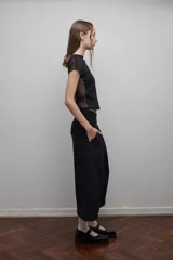 Camiseta negra de corte ajustado, con mangas cortas y espalda de tul transparente. Diseño versátil que permite usarla tanto de frente como de espalda.