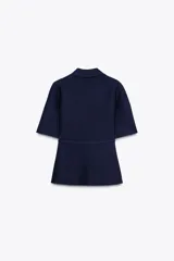Chaqueta azul marino de punto con cuello solapa y manga corta. Incluye cinturón fino con hebilla dorada y cierre frontal con botones a tono.
