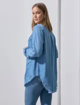 Camisa de jean celeste con flecos en el ruedo, de mangas largas y corte recto.