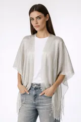 Poncho de punto fino color plateado con flecos en los bordes.
