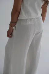 Pantalón palazzo color blanco hueso, de tiro alto y corte holgado. Confeccionado en lino.