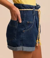 Short baggy de jeans azul oscuro, con cintura alta, trabillas, bolsillos y ruedo doblado. Incluye cinturón de cordón color crudo con borlas.