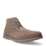 Botas tipo chukka de gamuza color taupe, con cordones y suela de goma gruesa. Presentan costura visible alrededor de la base y el logo de la marca grabado en el lateral.