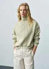 Sweater verde claro de punto medio con cuello alto y cierre de cremallera.