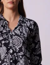 Blusa negra con estampado floral blanco, cuello mao con escote en V y abertura frontal con botones. Manga 3/4 con terminación fruncida.