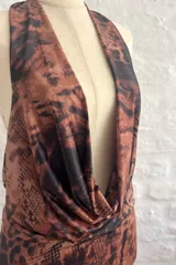 Vestido corto ajustado al cuerpo, con estampado animal print en tonos marrones y negros. Tiene escote en V pronunciado y breteles finos.