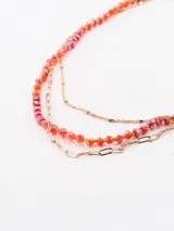 Collar dorado de tres hilos, dos de cadena y uno con cuentas de color naranja y rosa.