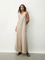 Mono largo color beige, de corte holgado, con cuello redondo y mangas cortas. Presenta bolsillos laterales y detalle de costuras verticales en el frente.