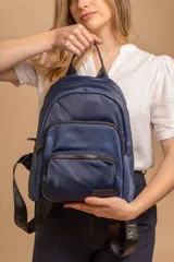 Mochila funcional color beige con detalles en negro, que incluye dos compartimentos con cierre y un bolsillo frontal para fácil acceso.