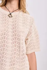 Top de punto crochet color crudo con mangas cortas y cuello redondo.