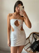 Minivestido blanco con lentejuelas, escote halter con tiras finas cruzadas, abertura en el pecho y recortes en los laterales.