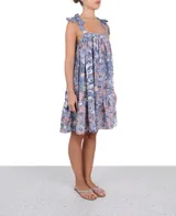 Vestido corto con estampado floral en tonos azul, blanco y rosa. Tiene breteles con lazos y falda con volados.