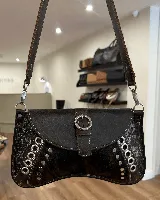 Cartera de cuero marrón con apliques de cuero con pelo y detalles metálicos.