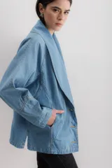 Chaqueta celeste de denim con cuello solapa, corte holgado y cierre frontal con botones dorados.
