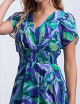 Vestido midi de gasa estampada con motivos florales en tonos azules y verdes. Escote en V tanto en la parte delantera como en la espalda. Corte en la cintura con punto smock y ruedo asimétrico.