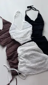 Conjunto de top y minifalda marrón con textura de encaje. El top es de corte halter y la falda es ajustada con cordones laterales.