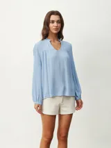 Blusa blanca de manga larga con escote en V y textura arrugada.