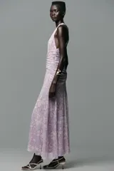 Vestido largo de tul color lila con estampado de flores blancas, cuello halter con lazada y escote pico.