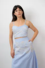 Conjunto de top corto con breteles finos regulables y falda midi con tajo lateral, ambos en color celeste y con bordado artesanal de diseño orgánico.