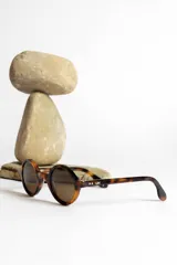 Lentes de sol con montura redonda negra y cristales verdes.