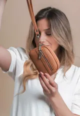 Monedero negro de simil cuero con correa para la mano, diseño práctico y compacto. Bolsillo principal con doble cierre, y un bolsillo frontal pequeño para llevar monedas.