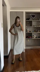 Vestido largo sin mangas, ajustado al cuerpo, con cuello redondo y estampado de rayas horizontales blancas y negras.