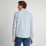 Camisa de vestir celeste con estampado de lunares pequeños, de corte clásico, manga larga y cuello italiano. Cierre frontal con botones.