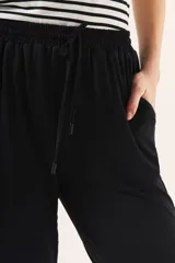 Pantalón babucha negro con cintura elastizada y cordón ajustable.