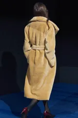 Abrigo largo color camel con efecto piel de oveja, cuello solapa, manga larga, bolsillos delanteros y cinturón ajustable con lazadas. Forro interior.
