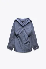 Camisa oversize a rayas verticales azules y blancas, de popelín, con cuello solapa, manga larga tipo murciélago acabada en puño con hombro caído, bolsillo de plastrón en delantero y cierre frontal con botones.