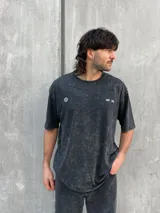Remera gris con efecto lavado, corte oversize y estampa en la espalda con texto y logo.