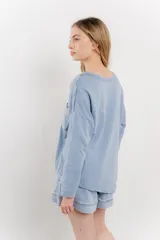 Remera celeste de manga larga con cuello redondo y bolsillo en el pecho.