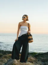 Pantalón negro de pierna ancha con cierre de gancho y cremallera, bolsillos laterales y detalle plisado.