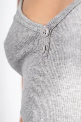 Vestido midi negro de punto canalé, con breteles finos, escote en V y dos botones decorativos.