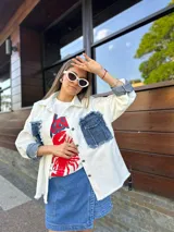 Sobrecamisa blanca de denim con cuello camisero, cierre frontal con botones a presión, mangas largas con puños abotonados, dos bolsillos de parche en el pecho con solapa y detalles desgastados en los bordes.