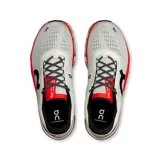 Championes de running On Cloudmonster 2, color blanco con detalles en negro, rojo y rosa.