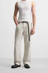 Pantalón de jean color beige, corte recto y relajado, con cintura ajustable con cordón interior, cinco bolsillos, efecto lavado y cierre frontal con cremallera y botón.