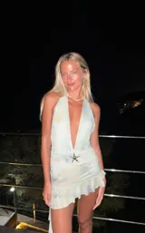 Minivestido celeste con estampado difuminado, escote halter con abertura en V y falda con volados. Presenta un aplique de estrella de mar en el centro.