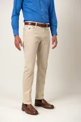 Pantalón de gabardina color beige, de corte recto, con cinco bolsillos y detalle de bordado de un pájaro en el bolsillo delantero.