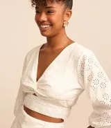 Blusa cropped de laise blanca con escote en pico, detalle torcido en el busto y manga corta abullonada.