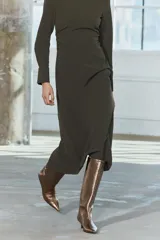 Vestido midi de cuello redondo y manga larga con puños. Tiene detalle de drapeado lateral y cierre trasero con cremallera oculta en la costura.