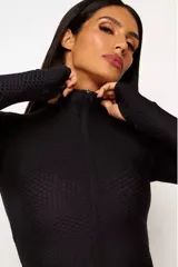 Campera negra de poliamida y elastano con textura tipo panal, cierre frontal completo, cuello alto y mangas largas con orificios para los pulgares.