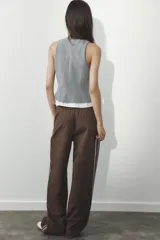 Pantalón de tiro alto negro a rayas verticales blancas, con cintura elástica ajustable con cordones, bolsillos delanteros y banda lateral blanca.